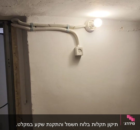 מנורה דולקת, שקע חשמל, צינור חשמל על קיר